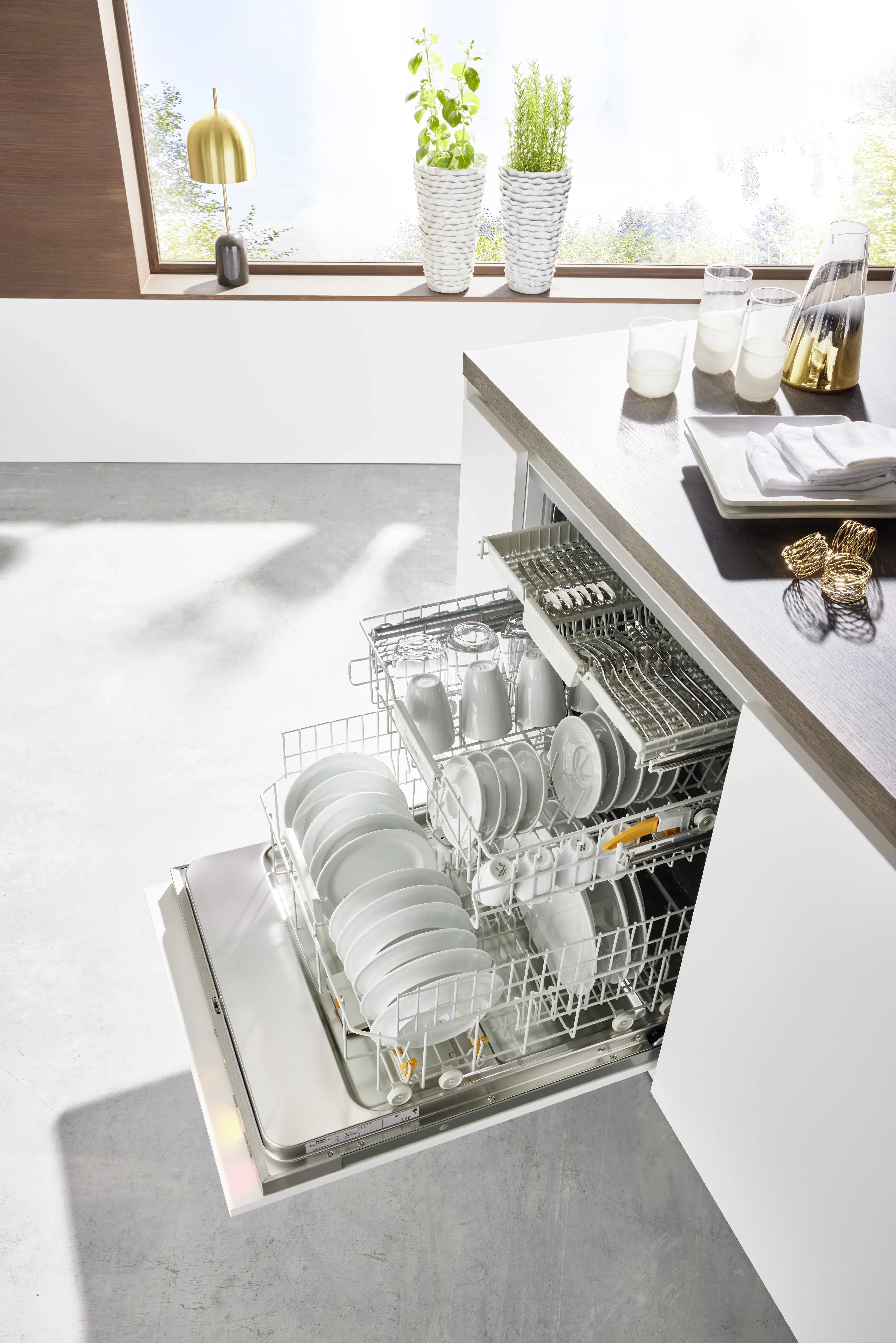 NOBILIA Alpinweiß mit Miele Geräten - Fokus auf Geschrisspüler, Drei Schubalden mit gelb-orangen Details innen und LED-Beleuchtung an der Tür